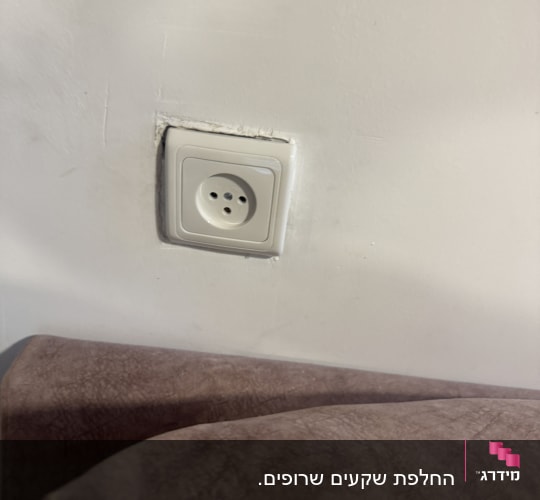 שקע חשמלי בקיר מעל ספה